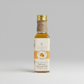 A bottle of cold pressed Himalayan apricot kernel oil with a label that reads 'Earth Reserve Apricot Kernel Oil'. The bottle is placed on a surface with a plant in the background.